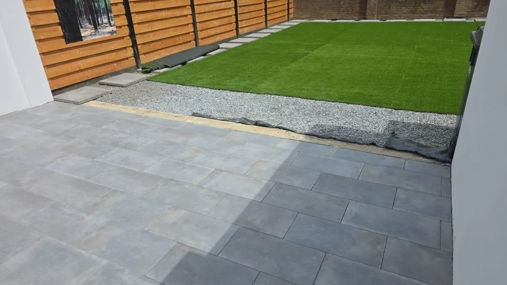 Aangelegde tuin in Zuid-Limburg: keramisch terras met grijze tegels, split-border en kunstgras.