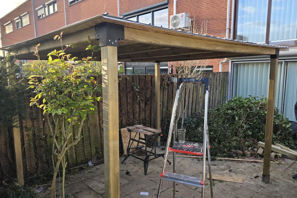 Veranda met houten draagconstructie en stalen dakplaten.