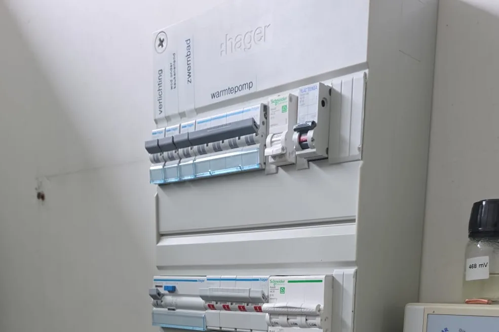 Hager groepenkast met aardlekautomaten en met de hand gelabelde groepen: verlichting, zwembad, warmtepomp.